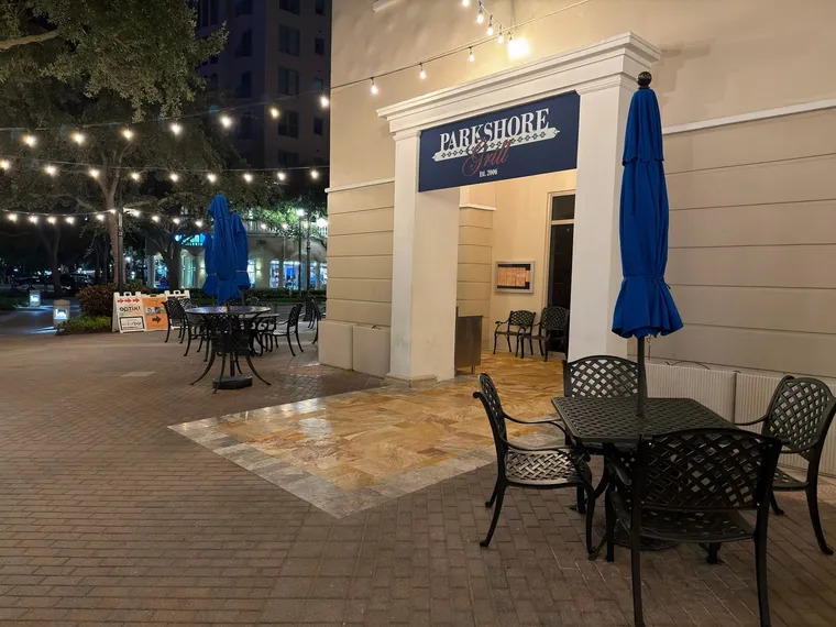 Wide nighttime view of a restaurant patio with freshly sealed gold travertine beneath string lights