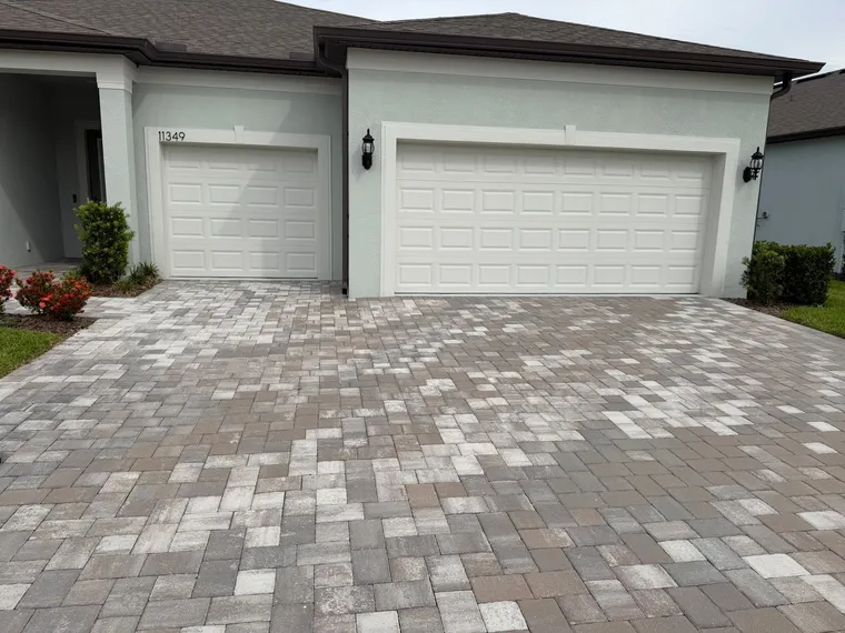 Paver driveway in front of a two-car garage after a deep clean, the gray film lifted off the surface