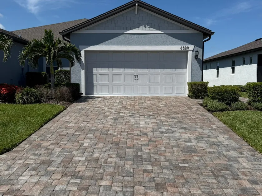 Paver driveway curing after sealer application, caution tape strung across the entrance