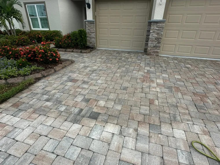 Sealed paver driveway and entry apron at a townhome, warm tan and gray pavers reading evenly across the field