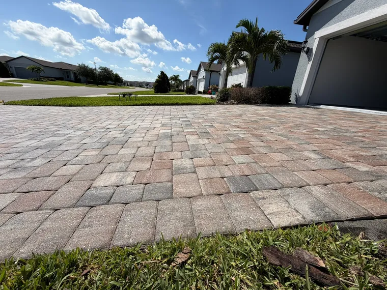 Low-angle view along a sealed tumbled paver driveway showing tight, fully sanded joints