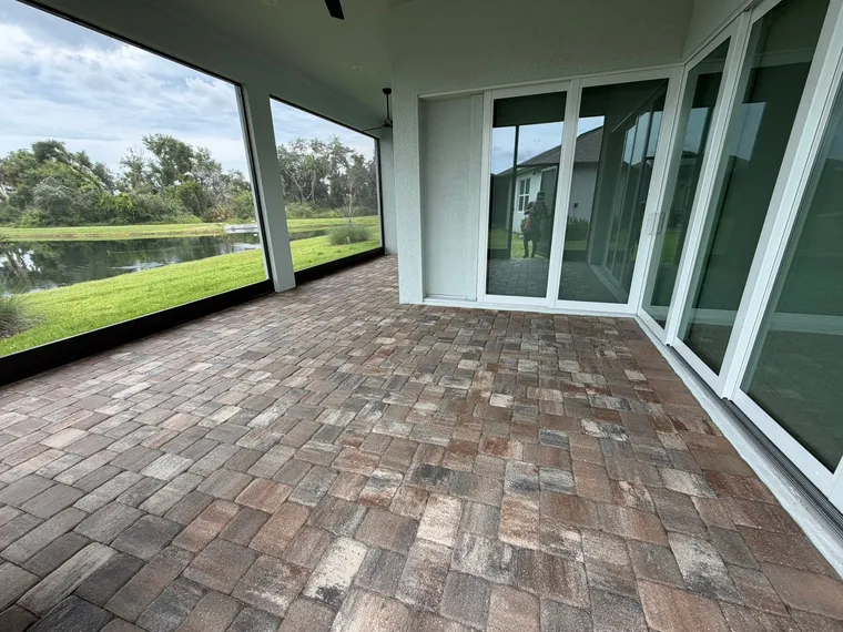 Sealed multicolor paver lanai inside a screen enclosure overlooking a pond