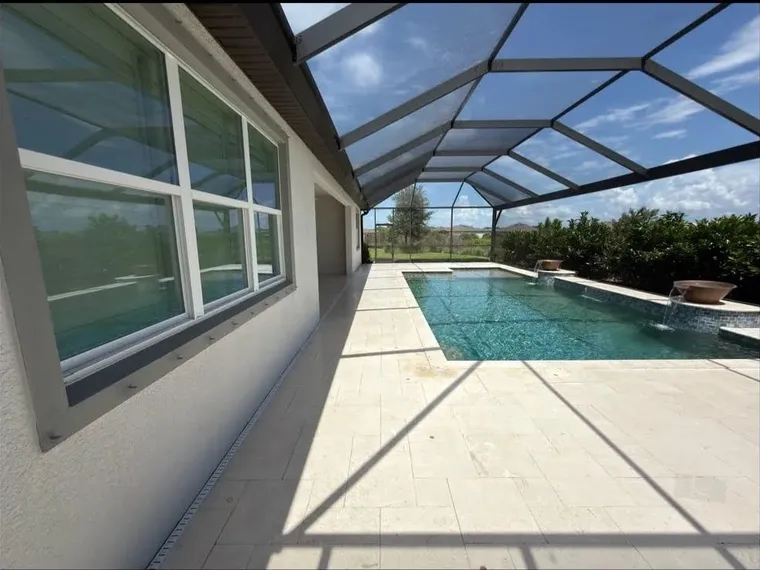 The same travertine pool deck after cleaning and restoration, with a bright even finish around the screened pool