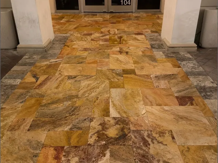 Sealed travertine entry floor at a commercial building, the stone showing deep gold and amber veining