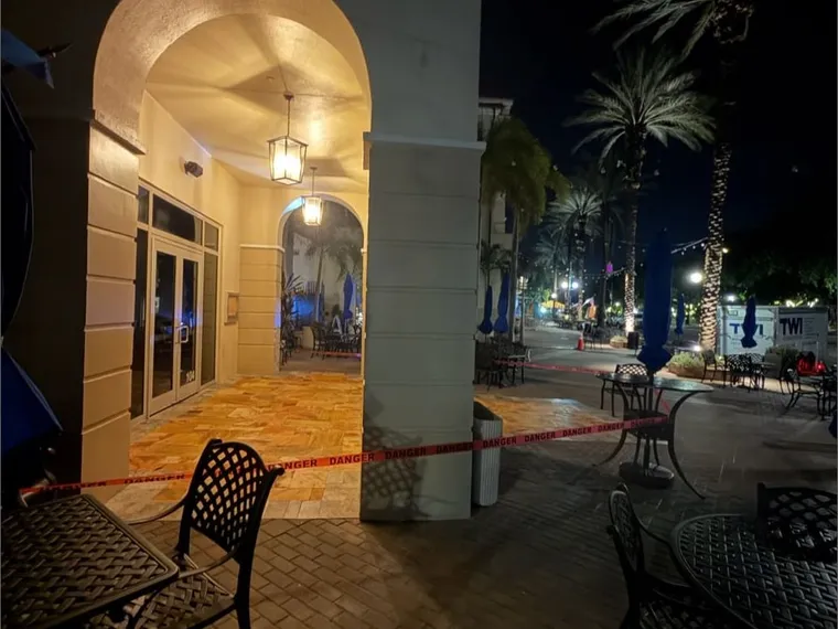 Commercial courtyard with sealed travertine paving photographed in the evening, bistro tables set out under an archway