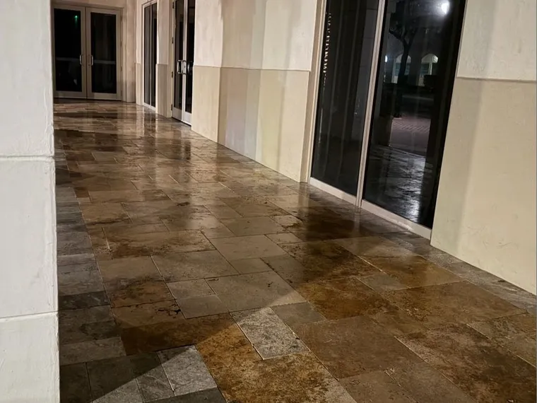 Covered commercial walkway with sealed travertine paving running the length of a storefront colonnade
