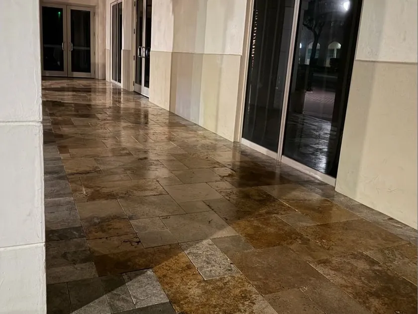 Covered commercial walkway with sealed travertine paving running the length of a storefront colonnade