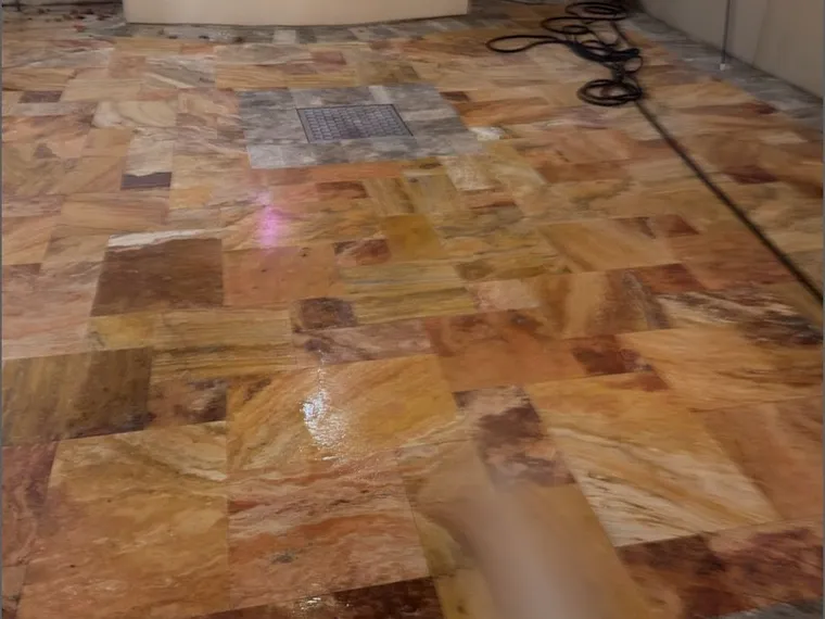 Travertine floor during sealer application, the wet surface reflecting overhead light