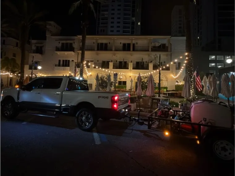 Truck and equipment trailer set up for an overnight commercial sealing job on a lit downtown street